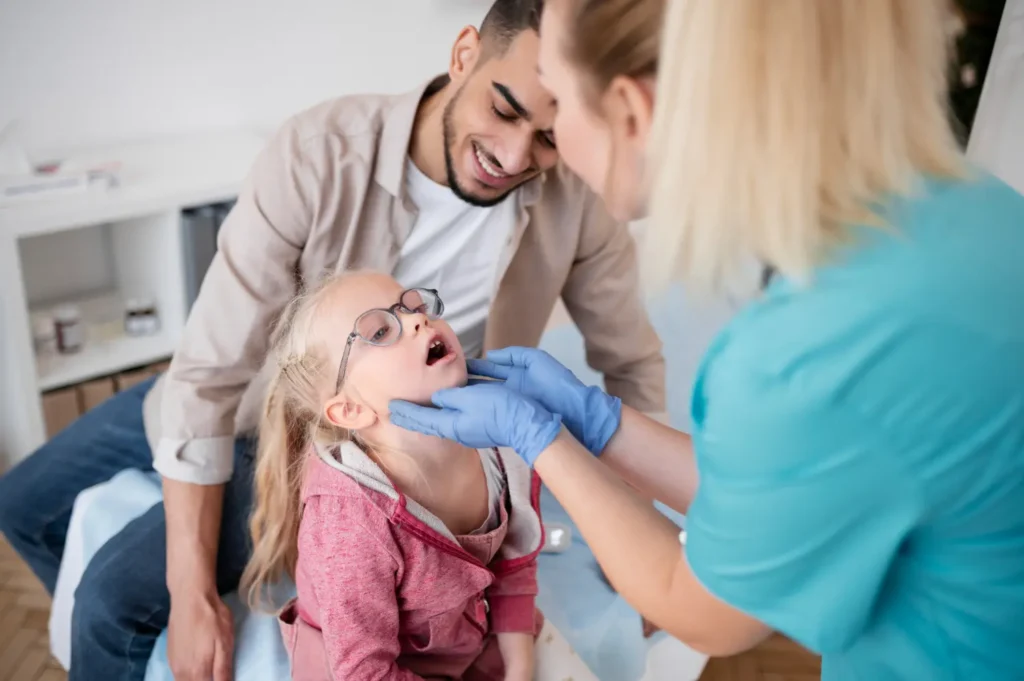 Odontopediatra de SOM revisando la sonrisa de un niño en la sala de su casa mientras sus padres observan tranquilos.